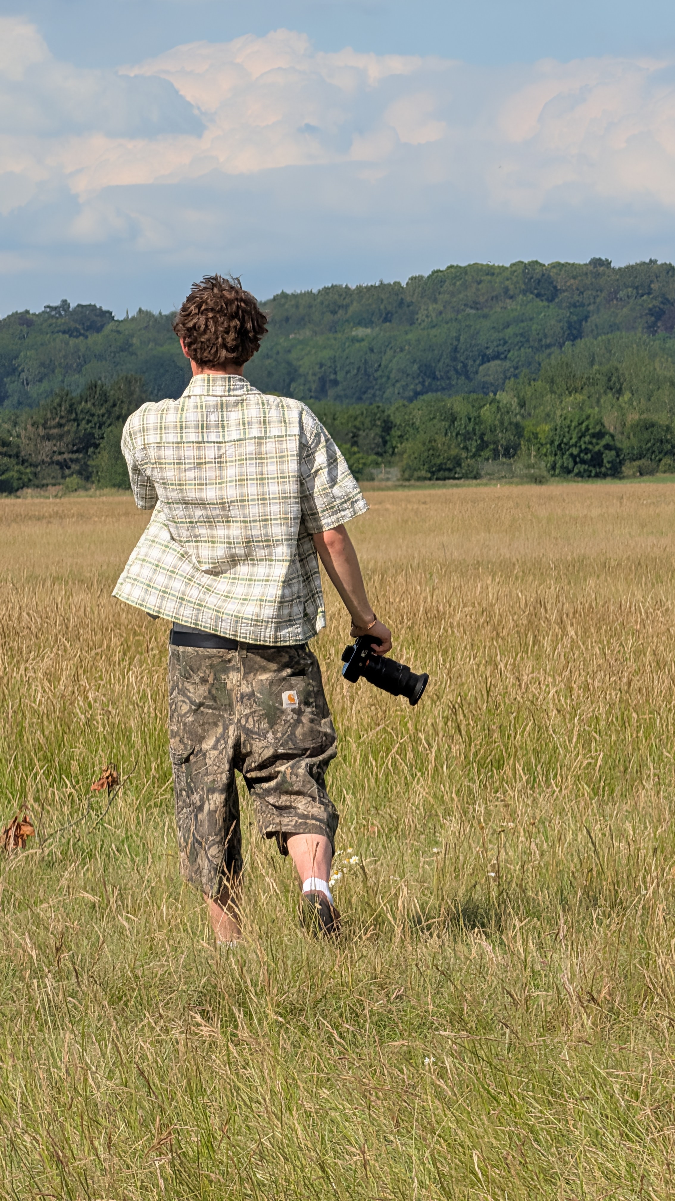 Kai Arnold standing in a field with his camera.